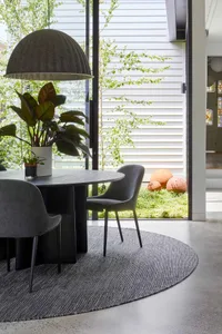 Modern living room with a wooden table, fabric chairs, and metal frame.