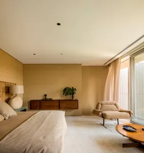 A modern minimalist bedroom featuring neutral textiles, wood accents, and a glass cabinet.
