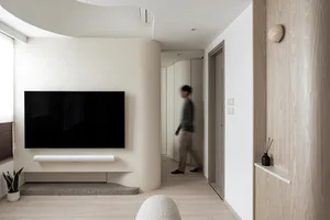 Minimalist living room featuring a sleek concrete fireplace and a large flat-screen TV on a white wall.