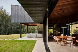 A modern residential exterior featuring wood, stone, and concrete materials.