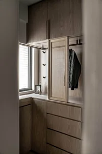 A modern wardrobe system with wooden storage units and a mesh-covered mirror.