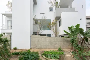 A minimalist residential building with a white exterior featuring concrete walls and a simple design.