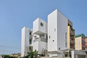 A modern, white-rendered building with concrete materials and minimalist design.