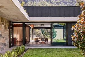 Modern residential house with stone, concrete, and glass exterior materials.