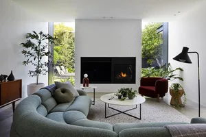 A modern living room featuring a green couch, coffee table, and fireplace.