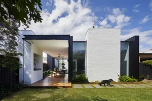 A modern minimalist home featuring white brick walls and large glass windows.