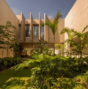 Modern residential architecture featuring wooden columns, glass walls, and concrete structure.