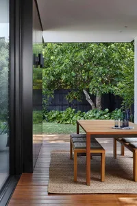 Modern outdoor seating area with wooden table, greenery, and trees