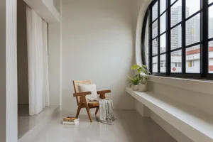 A minimalist living room with a window, a wooden chair, and green plants