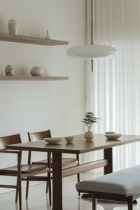A modern dining room featuring wooden tables, glass vases, and fabric seating.