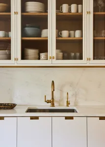 A modern kitchen featuring marble countertops and brass fixtures.