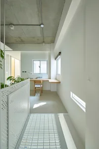 Minimalist office space with concrete floor and walls, featuring a simple wooden desk and chair, and a small window.