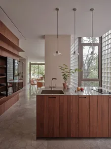 Modern residential kitchen featuring wooden cabinets, a glass-block wall, and a contemporary design.