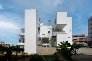 White concrete residential building with greenery.