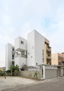 Modern, single-story house with white concrete exterior, featuring several levels and balconies.