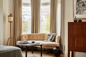 Modern living room featuring a comfortable sofa near a window with curtains, creating a welcoming and cozy atmosphere.
