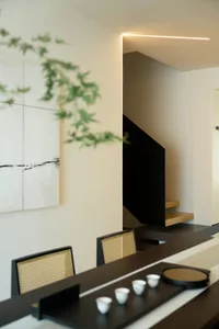 Modern dining room with concrete walls, wooden table and chairs, and minimalist decor.
