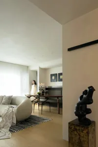 Modern minimalist residential interior with wooden flooring, white plaster walls, and minimalistic furniture with black accen