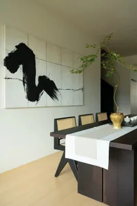 Minimalist dining room featuring wooden furniture and a black and white abstract painting on the wall.