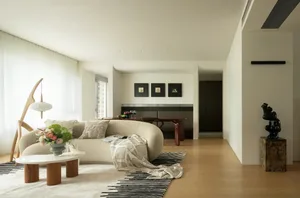 A minimalist living room with neutral-colored textiles, a modern floor lamp, and a contemporary sofa and coffee table.