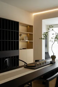 Modern home office featuring a wooden desk and shelving unit with abstract sculptures and lighting.