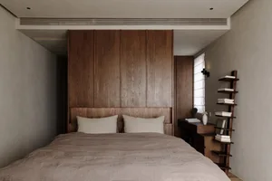 A serene minimalist bedroom featuring a bed with natural wooden headboard and a wooden bookshelf against the wall.