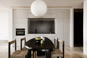 A modern minimalist kitchen with black table, white cabinets, and granite countertops.