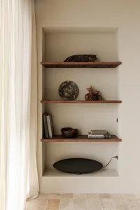 Three wooden shelves with rustic decor items such as a plate, figurines, and books.