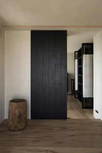 Modern minimalist bedroom featuring a black wood panel wall on a wooden floor.