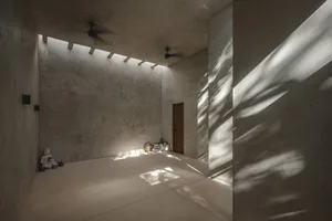 極簡風格的房間，地板與牆面鋪設混凝土或大理石瓷磚，擺放佛像與裝飾物品
