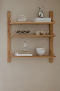 A minimalist arrangement of wooden shelves containing various decorative and functional items such as books, a glass decanter