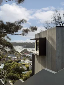 A modern building with a metallic exterior overlooking a bay with boats.