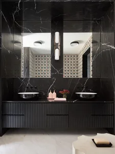 Modern bathroom featuring black marble countertops, sinks, and wall tiles.