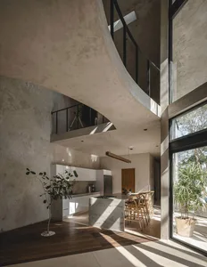 A modern home interior featuring a concrete kitchen with a lofted space and large windows.