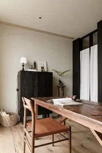 A modern home office featuring a wooden table and chair, minimalist decor, and natural lighting.