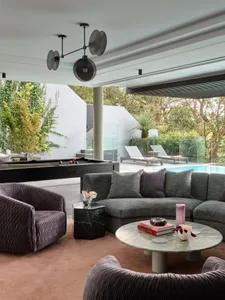 Modern living room featuring a comfortable L-shaped sofa upholstered in textured fabric, complemented by round tables, armcha