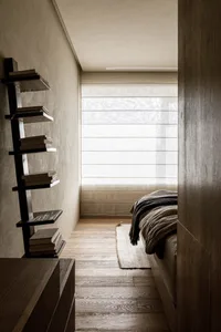 A minimalist bedroom with wooden floors and a bed.