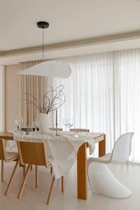 Modern minimalist dining room with a wooden table, white chairs, and a white fabric lampshade.