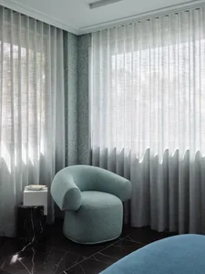 A modern residential interior featuring a textured fabric curtain in a light, airy space with a dark marble floor and a vinta