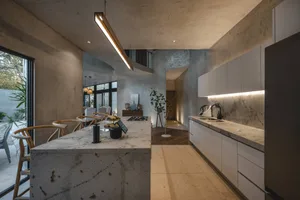 Modern industrial kitchen with concrete walls, stone counter, and minimalist design.