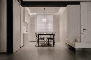 A minimalist dining room featuring concrete walls and a black metal table with chairs.