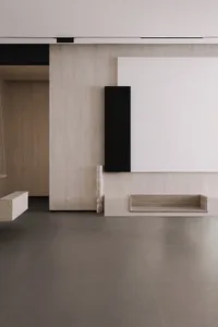 A minimalist entryway featuring concrete flooring and walls with a large white panel and black wall art.