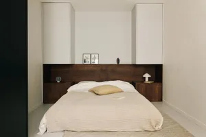 Minimalist bedroom with a wooden bed and white bedding.