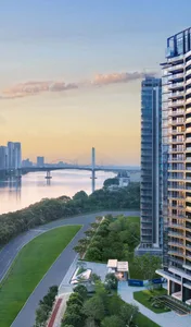 A modern apartment building with glass façades overlooking a river at sunset.