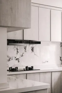 Modern kitchen with white marble backsplash and white wooden cabinets