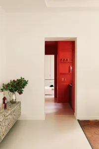 A modern living room with white walls and a red door.