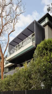Modern residential building with black metal elements and greenery.