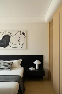 Modern minimalist bedroom featuring a black bed frame, white bedding, and a black and white abstract painting above the bed.