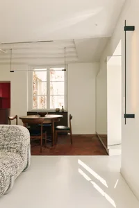 Minimalist living room with concrete walls and floor, featuring a modern sofa and dining table with chairs.