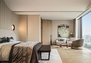 Modern bedroom featuring a bed with fabric bedding and wooden headboard, a small sofa, and a painting on the wall.
